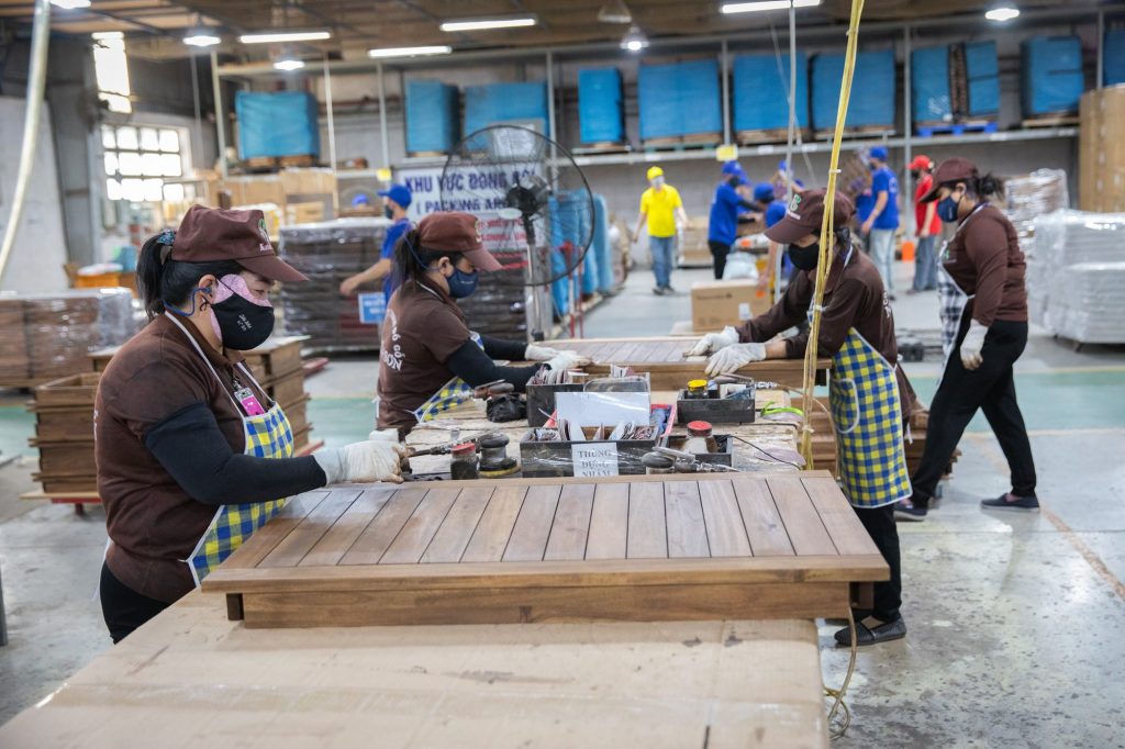 Furniture sourcing for importers: workers finishing a wooden table at Nghia Son